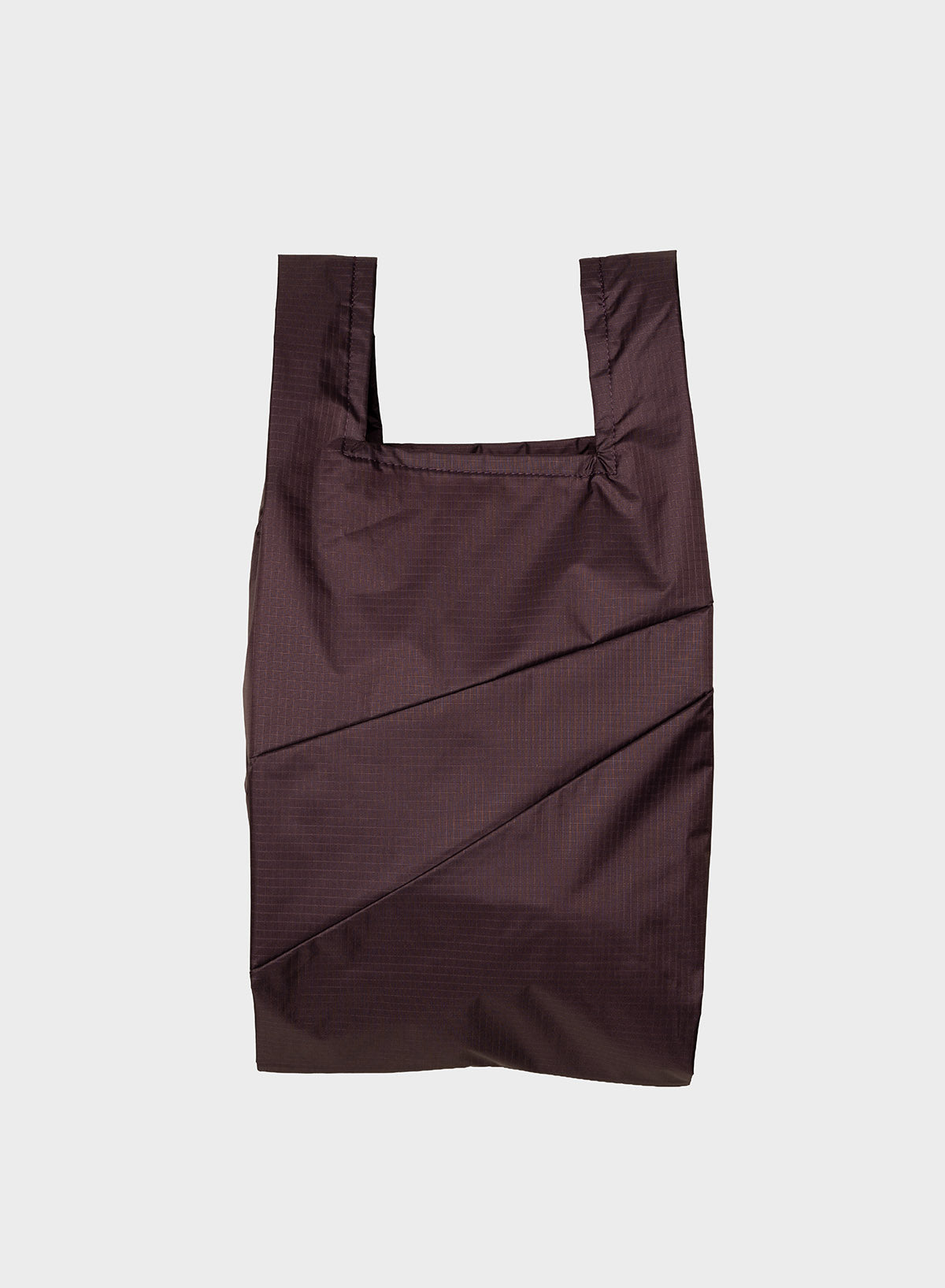 A dark brown reusable plastic bag with a subtle grid texture, featuring integrated shoulder straps and diagonal stitched paneling, shown against a light gray background.
