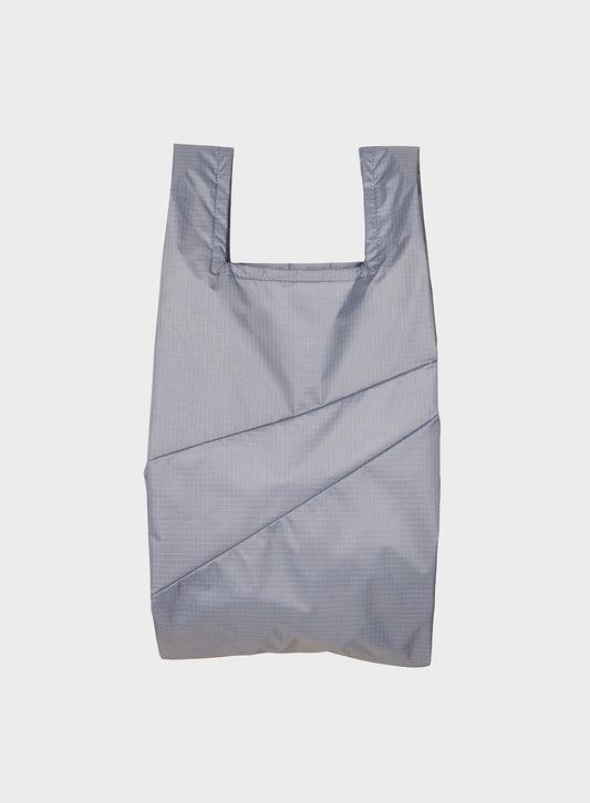 A light gray reusable plastic bag with a subtle grid pattern and diagonal stitched details, shown against a plain light gray background.