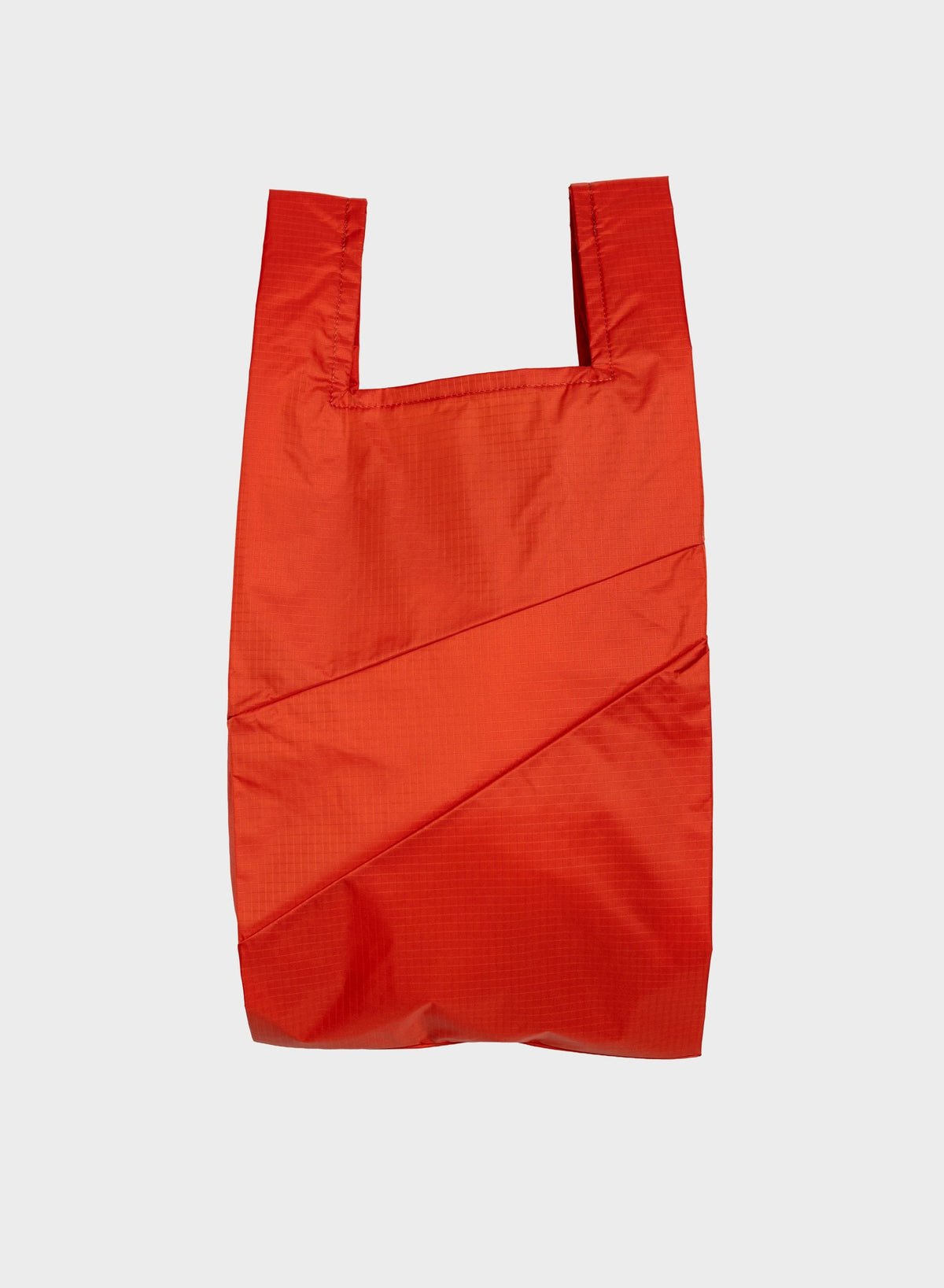 A bright red reusable plastic shopping bag with integrated shoulder straps, shown flat against a light gray background.