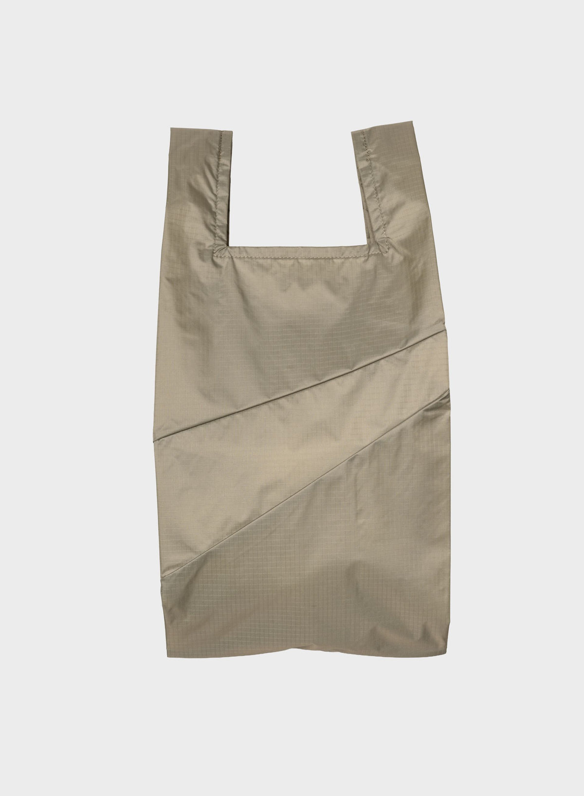 A light beige reusable plastic bag with integrated shoulder straps and diagonal seam details, shown flat against a light gray background.