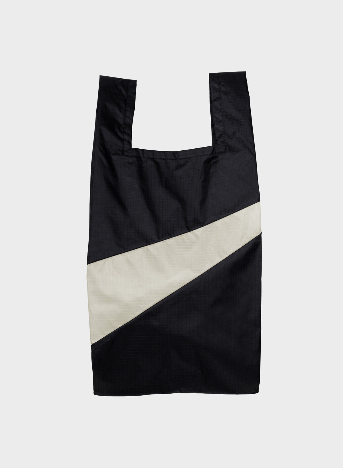 A black reusable plastic bag with a wide diagonal white stripe across the front, photographed flat against a light gray background.